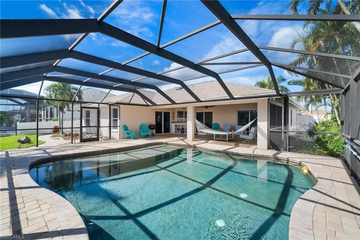 View of pool with a patio area and glass enclosure