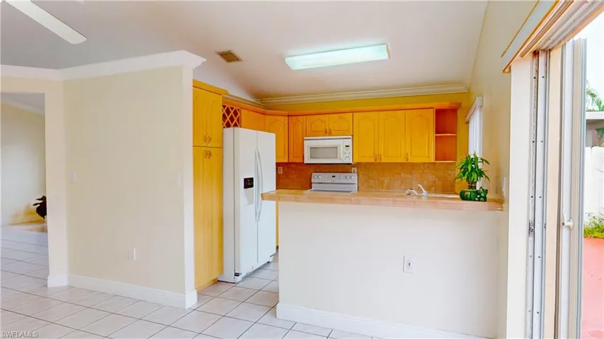 Kitchen with white appliances, a peninsula, ornamental molding, tasteful backsplash, and open shelves