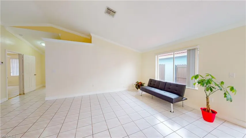 Sitting room featuring lofted ceiling, crown molding, and light tile patterned floors