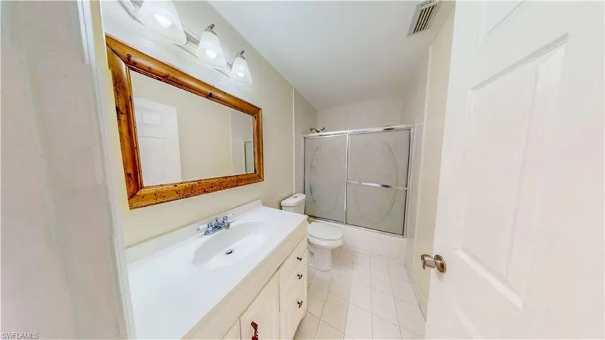 Full bathroom featuring vanity, bath / shower combo with glass door, and light tile patterned floors