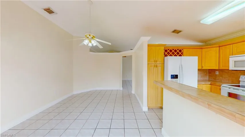 Kitchen featuring white appliances, ornamental molding, a ceiling fan, light tile patterned floors, and backsplash