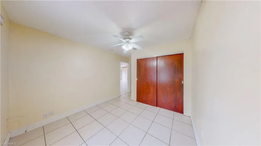 Unfurnished bedroom with a ceiling fan, a closet, and light tile patterned floors