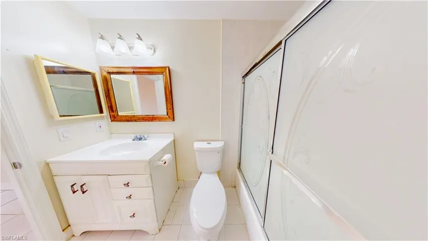 Full bath featuring a shower with door, vanity, and light tile patterned flooring