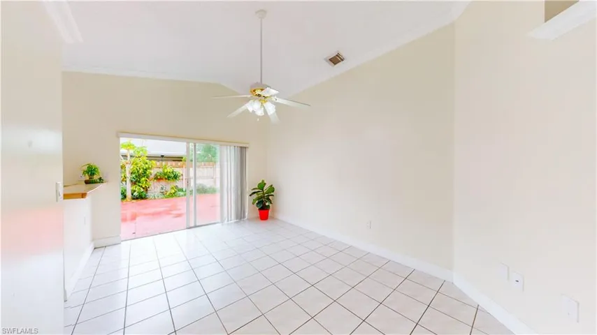 Empty room with ornamental molding, light tile patterned flooring, a ceiling fan, and vaulted ceiling