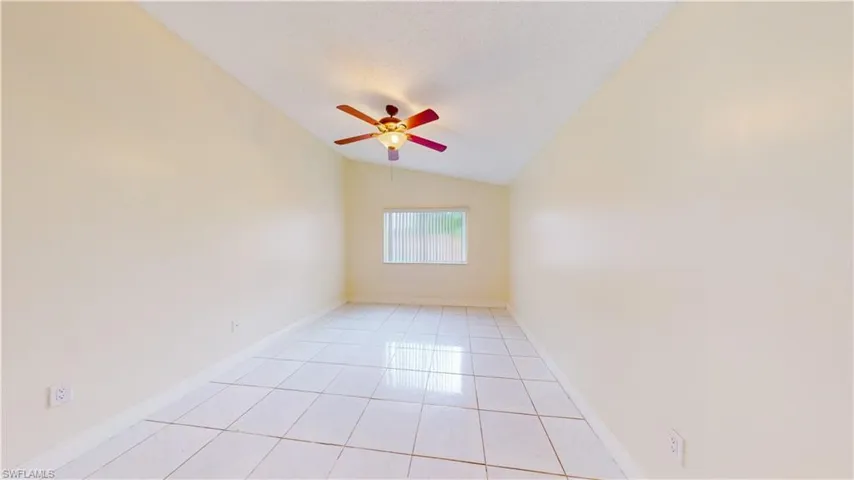 Spare room featuring a ceiling fan, light tile patterned flooring, and lofted ceiling