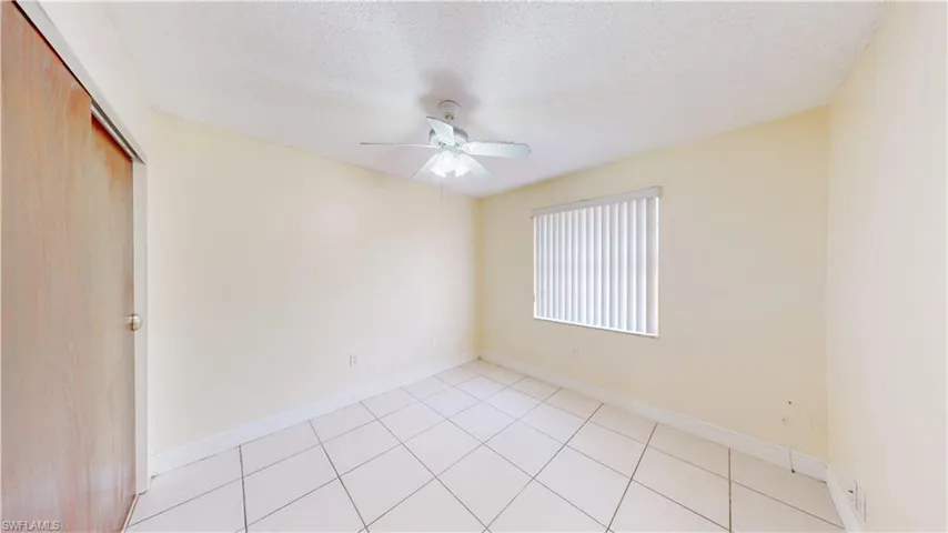 Unfurnished room featuring a textured ceiling, ceiling fan, and light tile patterned flooring