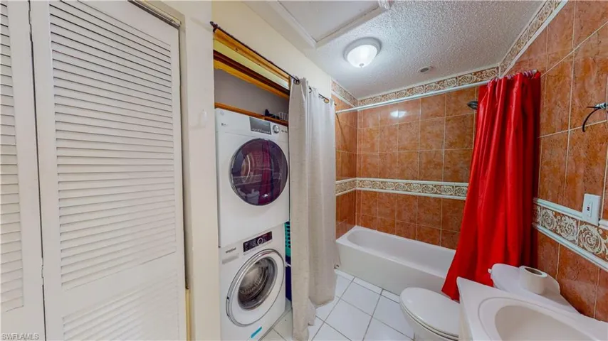 Full bath with a closet, a textured ceiling, tile patterned flooring, shower / bath combo, and vanity