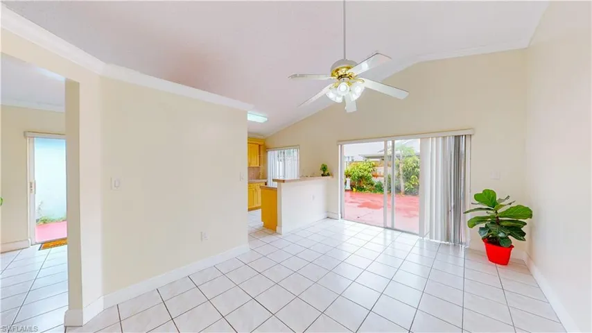 Empty room featuring ornamental molding, vaulted ceiling, a ceiling fan, and light tile patterned flooring