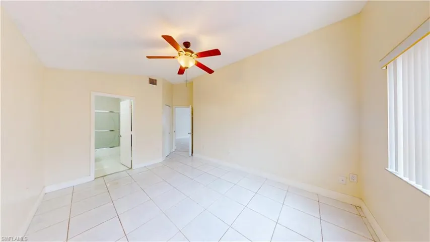 Empty room featuring ceiling fan, light tile patterned flooring, and lofted ceiling