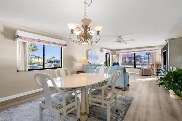 Dining space featuring a chandelier, healthy amount of natural light, wood finished floors, and a ceiling fan