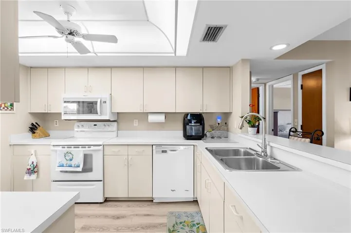 Kitchen with white appliances, light countertops, a ceiling fan, light wood finished floors, and cream cabinets