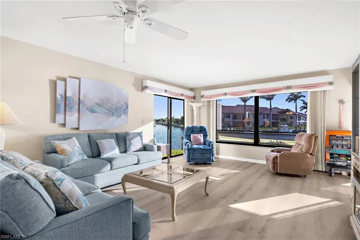 Living room with wood finished floors, a water view, and ceiling fan