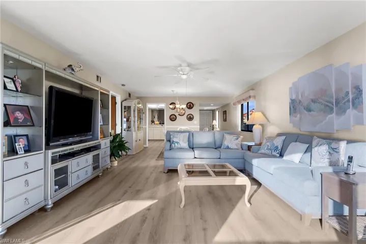 Living area with ceiling fan, light wood-style flooring, and a chandelier