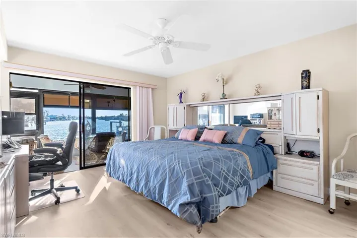 Bedroom featuring multiple windows, light wood-style floors, an office area, and access to outside
