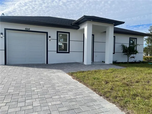 Ranch-style house featuring a front yard, decorative driveway, and stucco siding