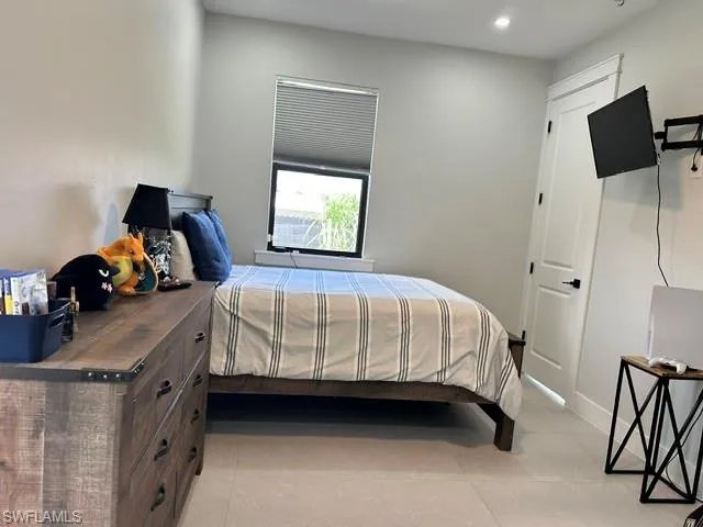 Recessed lighting, window with horizontal blinds, white interior door with dark hardware, light-toned flooring, and wall-mounted television bracket
