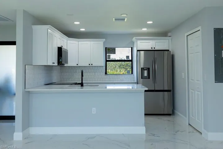 Kitchen with stainless steel appliances, white cabinetry, tasteful backsplash, and sink