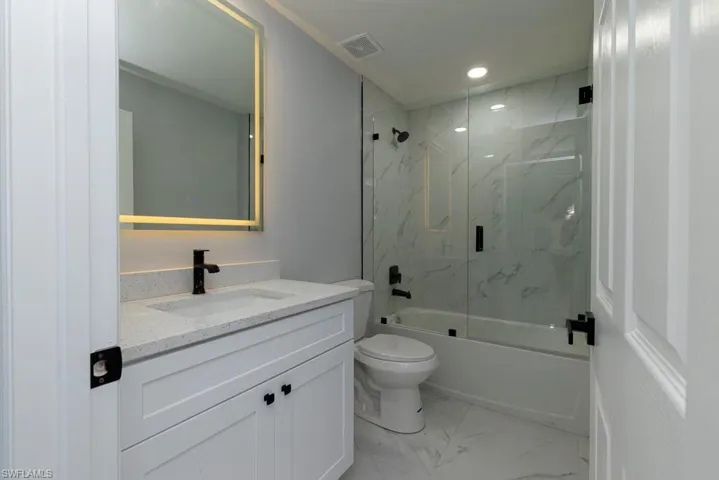 Full bathroom with vanity, toilet, and enclosed tub / shower combo