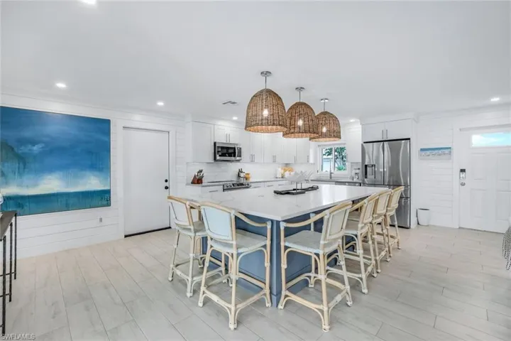 Kitchen featuring a center island, white cabinetry, hanging light fixtures, a kitchen breakfast bar, and stainless steel appliances