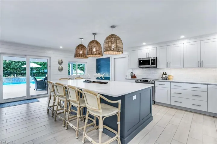 Kitchen with white cabinetry, a center island, stainless steel appliances, and decorative light fixtures