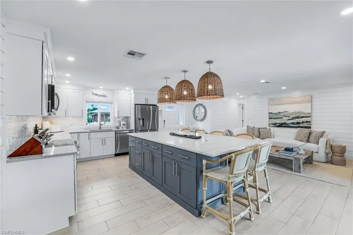 Kitchen featuring sink, decorative light fixtures, white cabinetry, appliances with stainless steel finishes, and a center island