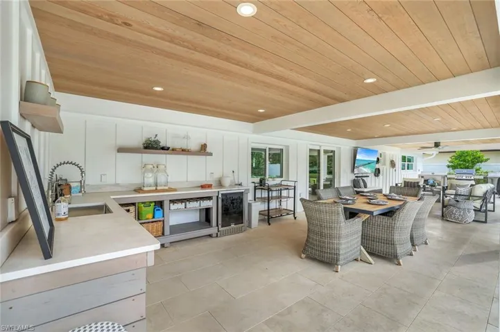 Dining area featuring wood ceiling, sink, beverage cooler, light tile patterned floors, and ceiling fan