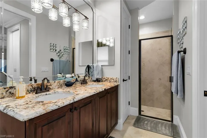 Full bathroom with double vanity and a stall shower