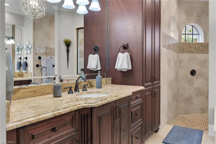 Bathroom with walk in shower, vanity, and hanging lights