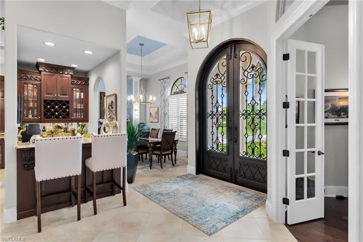 Entryway featuring a chandelier, french doors, arched walkways, ornamental molding, and a raised ceiling