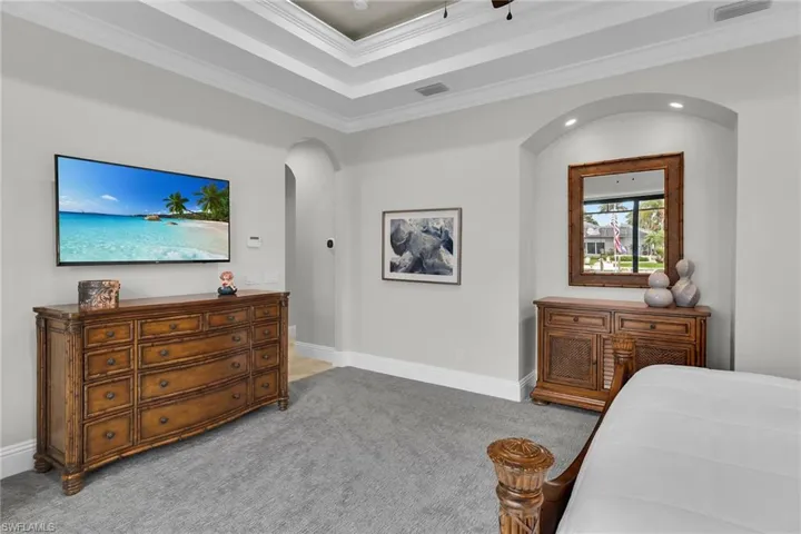 Bedroom with carpet floors, crown molding, and arched walkways