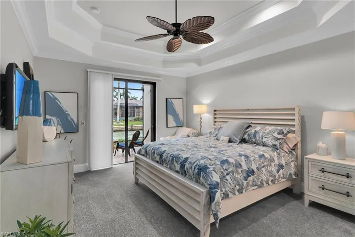 Carpeted bedroom with ornamental molding, access to outside, ceiling fan, and a water view