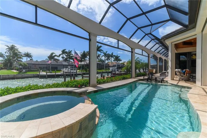 Integrated pool / spa with a sunroom, a patio area, glass enclosure, a water view, and a boat dock