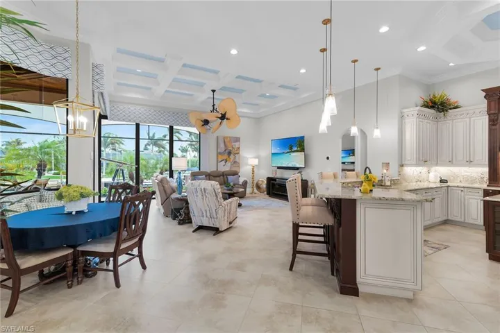 Kitchen with coffered ceiling, a ceiling fan, light stone countertops, a kitchen bar, and open floor plan