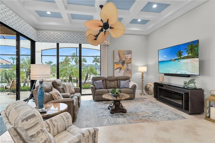 Living room featuring coffered ceiling, ornamental molding, and recessed lighting