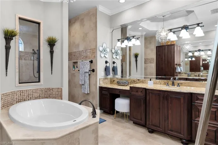 Bathroom with vanity, hanging lights, ornamental molding, a walk in shower, and a bath