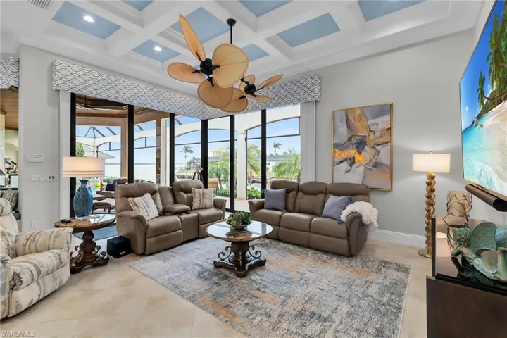 Living area featuring coffered ceiling, plenty of natural light, ceiling fan, and ornamental molding