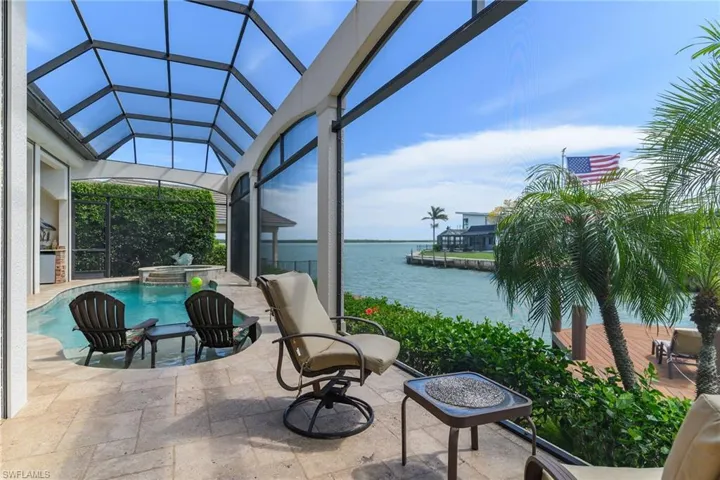 View of patio with a sunroom, a pool with connected hot tub, a water view, and a lanai