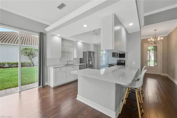Kitchen with light countertops, plenty of natural light, a sink, a peninsula, and appliances with stainless steel finishes