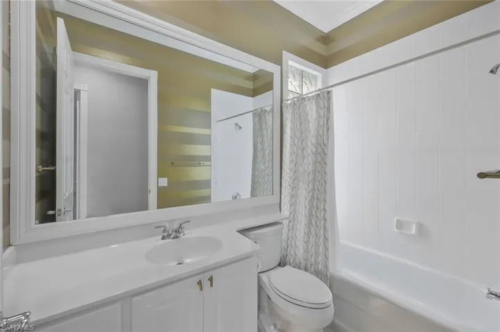 Full bathroom featuring shower / bath combination with curtain, crown molding, toilet, and vanity