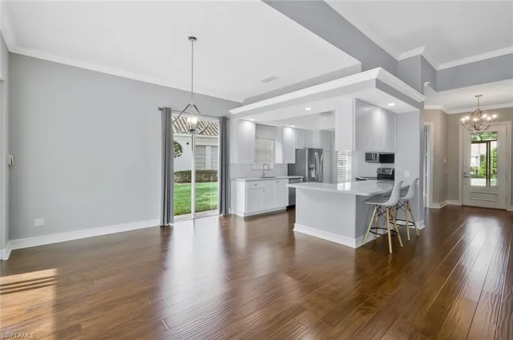 Kitchen with dark wood-style flooring, a peninsula, appliances with stainless steel finishes, and a chandelier