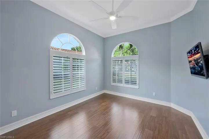 Empty room featuring baseboards, ornamental molding, a ceiling fan, and dark wood finished floors
