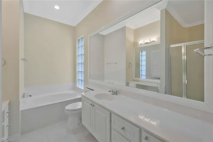 Full bathroom with vanity, crown molding, and a bath