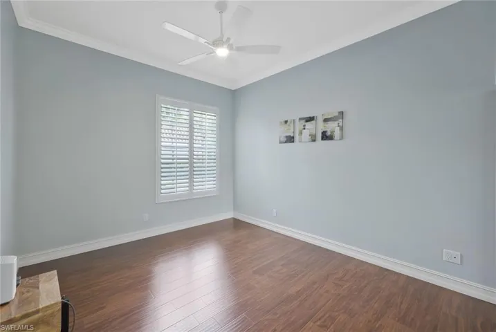 Spare room featuring dark wood finished floors, ornamental molding, baseboards, and ceiling fan