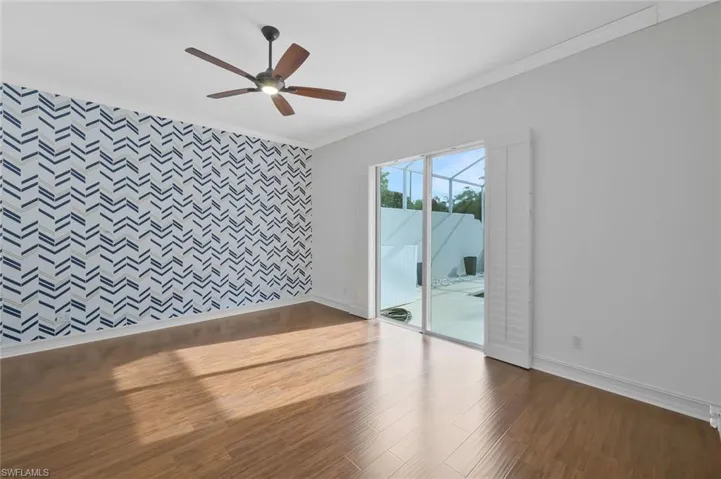 Unfurnished room featuring baseboards, wood finished floors, ornamental molding, and an accent wall