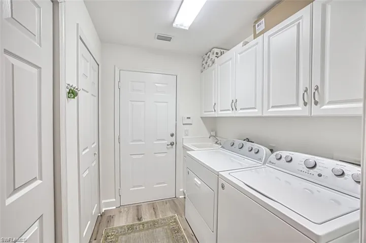 Laundry room featuring light wood-type flooring, cabinet space, and independent washer and dryer
