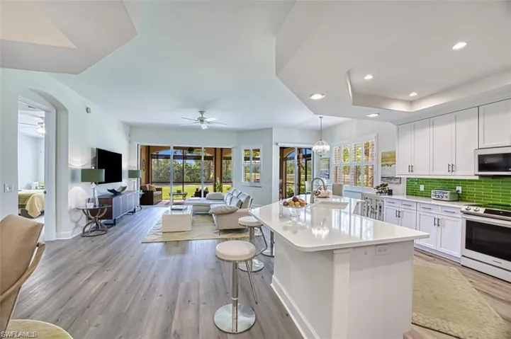 Kitchen with white microwave, ceiling fan, stainless steel range with electric cooktop, open floor plan, and white cabinets