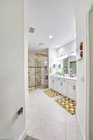 Bathroom featuring double vanity, a shower stall, tile patterned floors, baseboards, and recessed lighting
