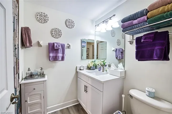 Bathroom with vanity, toilet, wood finished floors, and baseboards