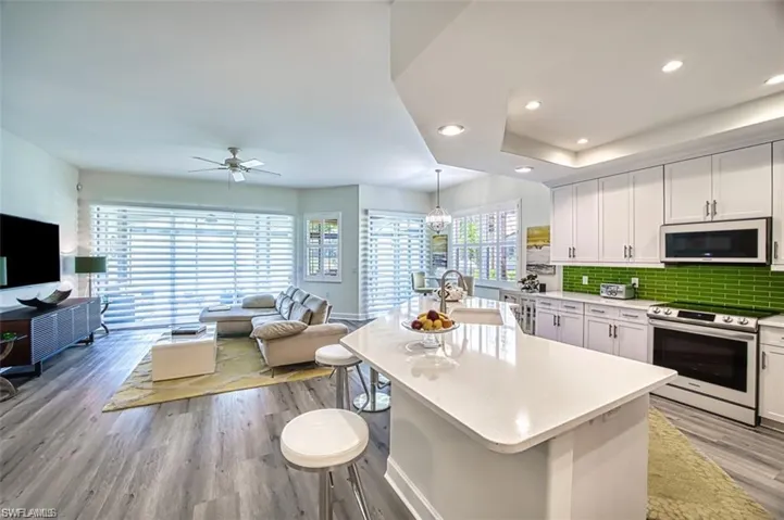 Kitchen with electric stove, white microwave, a sink, open floor plan, and light wood-type flooring
