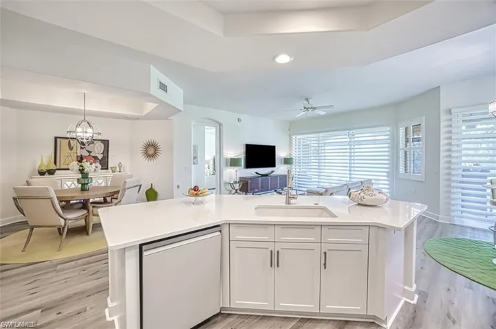 Kitchen featuring dishwasher, a sink, a tray ceiling, open floor plan, and recessed lighting